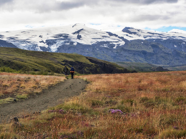 Couple of hikers with backpacks on the trail overlooking the mountains, Iceland - Photo, image