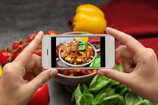 Woman taking photo of yummy stew at kitchen table - 写真・画像