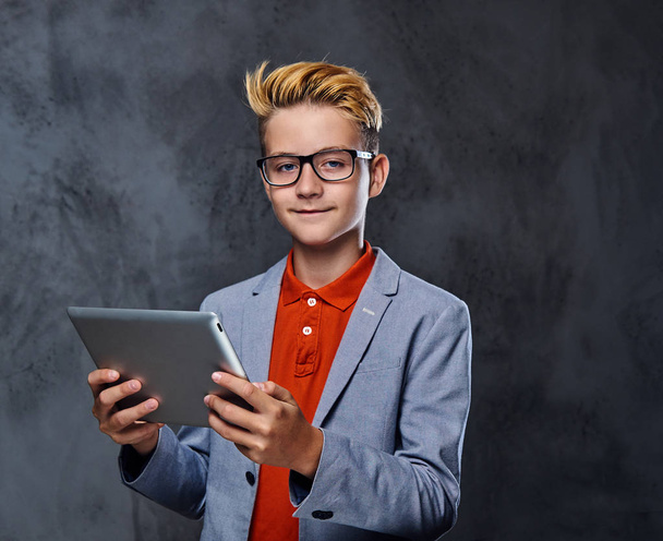 A boy in eyeglasses holds tablet PC. - Фото, изображение