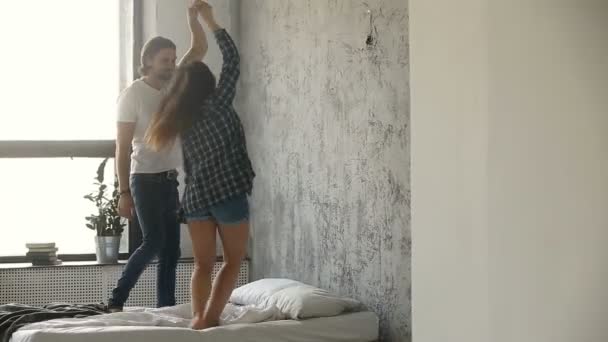 Young couple dancing on bed, rehearsing wedding dance in bedroom - Кадри, відео
