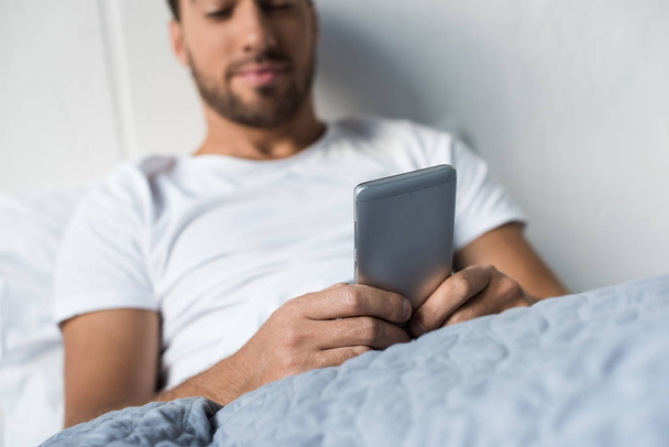 man using smartphone in bed - Foto, Imagen