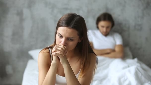 Unhappy couple sitting apart on bed, woman worried after conflict - Video