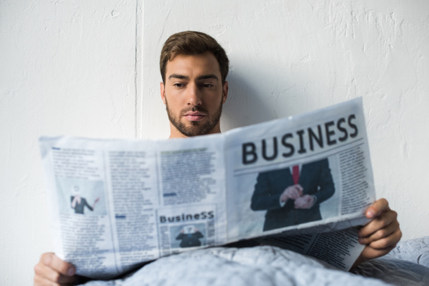 Hombre en la cama leyendo el periódico
 - Foto, Imagen