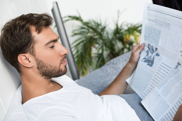 Hombre en la cama leyendo el periódico
 - Foto, Imagen