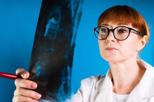 woman doctor in glasses carefully examines x-ray sheet - Foto, imagen