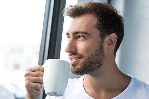 Улыбающийся мужчина пьет кофе
 - Фото, изображение