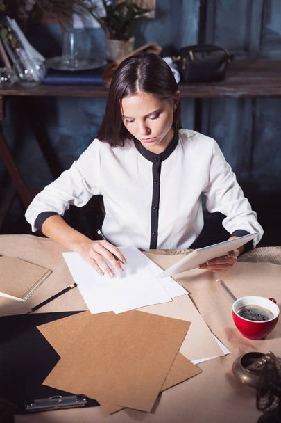 Young beautiful woman working with cup of coffee and notebook at loft office - Foto, Bild