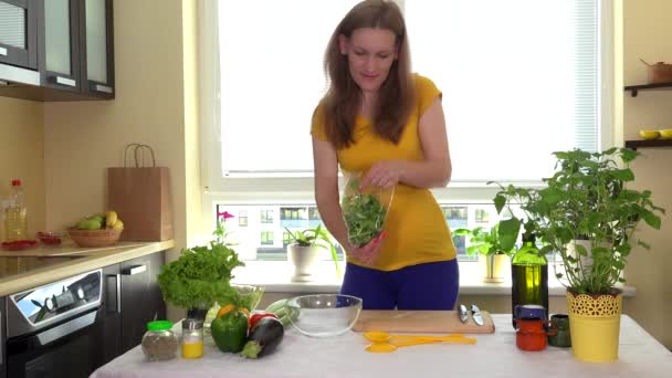 Embarazada esposa unbox ensalada verde hojas y poner en plato de vidrio en la mesa de la cocina
 - Metraje, vídeo