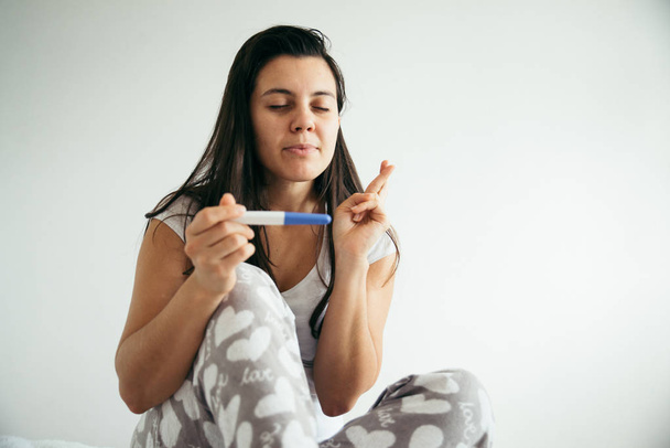 Mladá žena ve štěstí při pohledu na pregnance testu - Fotografie, Obrázek