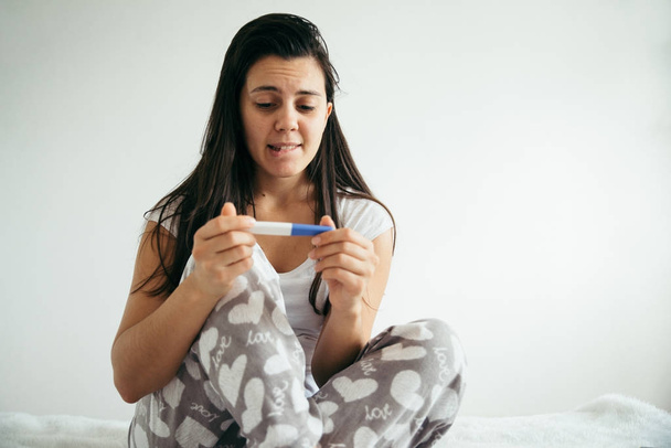 woman in bed surprised by pregnancy test - Photo, Image