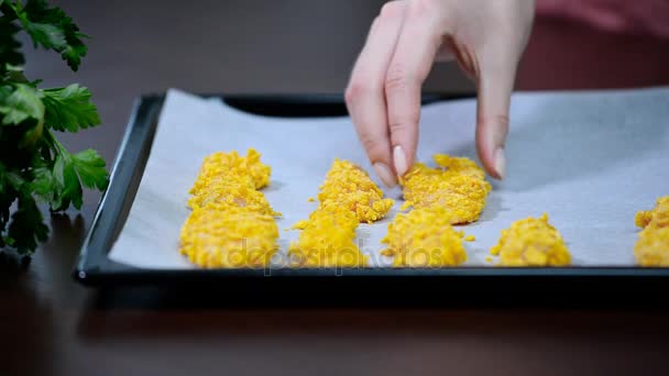 Meisje zet kip stripsy op een ovenschaal - Video