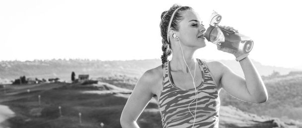 Fitness and magical views of Tuscany. healthy active woman in sport clothes against scenery of Tuscany drinking water - Zdjęcie, obraz