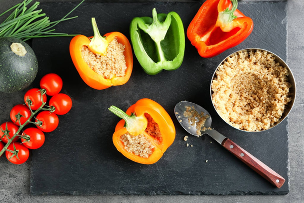 Composition with quinoa stuffed peppers and vegetables on kitchen table - Photo, Image