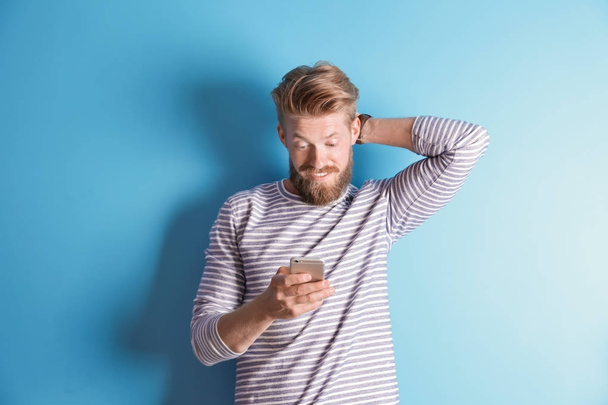 Young hipster man using smartphone on color background - Φωτογραφία, εικόνα
