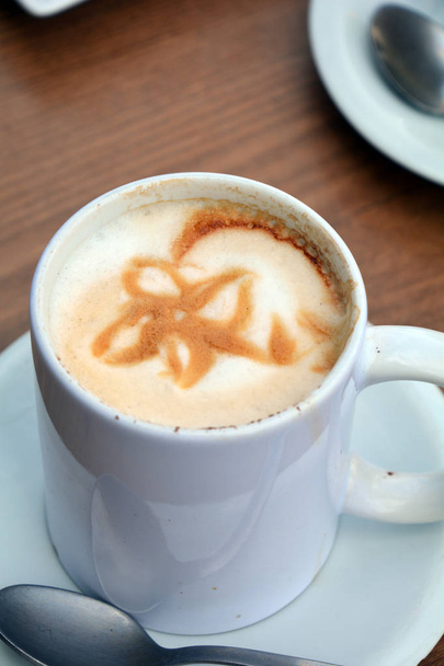 Tasse schäumenden Cappuccino auf einem Teller auf einem Holztisch. - Foto, Bild