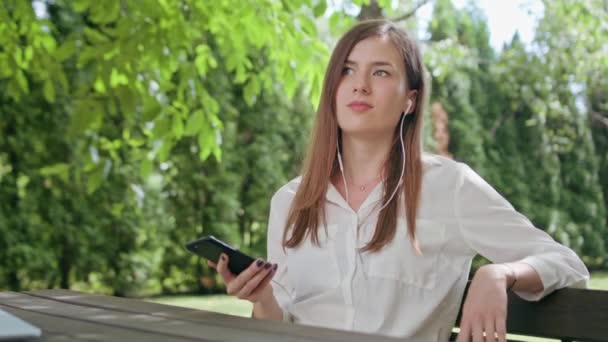 Lady στο πάρκο να ακούτε μουσική στο τηλέφωνο - Πλάνα, βίντεο