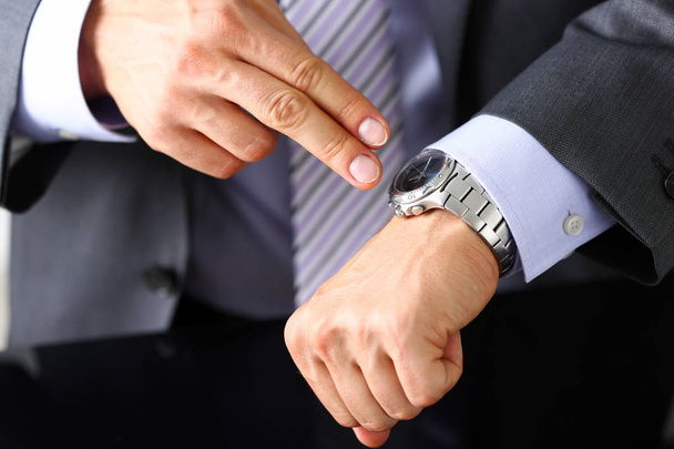 Homem de terno e gravata check-out tempo no relógio de pulso de prata
 - Foto, Imagem