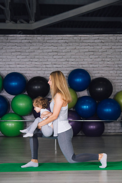 Mother and baby girl do exercises together in the gym - Photo, Image