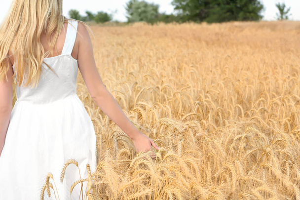 Young woman touching wheat in field - Foto, Bild