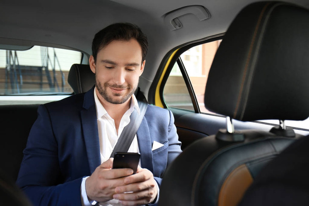 Handsome man with phone sitting in taxi car - Foto, afbeelding