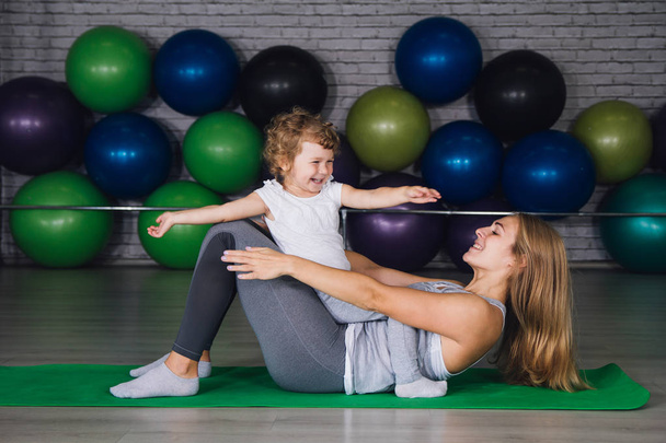 Mother and baby girl do exercises together in the gym - Fotografie, Obrázek