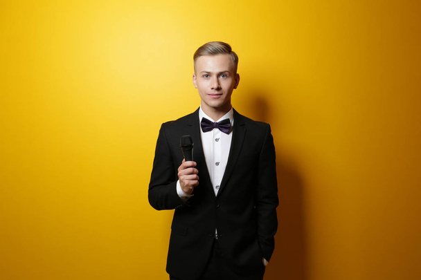 Young presenter with microphone on color background - Foto, immagini