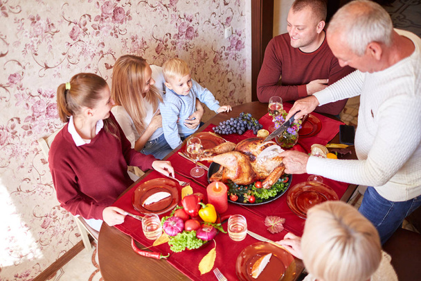 Ευτυχισμένη οικογένεια στο τραπέζι γιορτάζει την ημέρα των ευχαριστιών σε ένα θολή φόντο. Παραδοσιακή αντίληψη για την ημέρα των ευχαριστιών. - Φωτογραφία, εικόνα