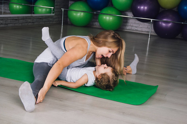 Mother and baby girl do exercises together in the gym - Foto, Imagem