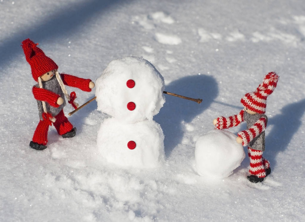  dřevěné panenky v červené pletené oblečení valí sněhové koule se buil - Fotografie, Obrázek
