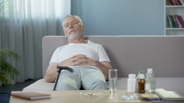 Relax after taking pills. Senior man sleeping on sofa at home. Medication - Filmati, video