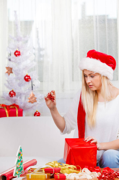 Woman in Santa hat opening christmas gifts - 写真・画像