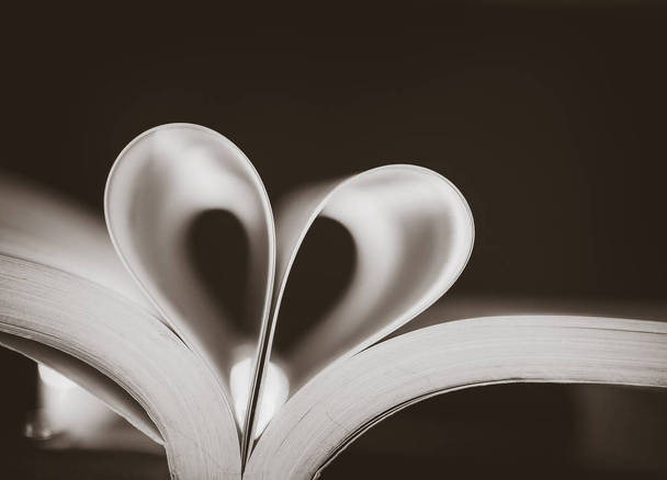 Pagine di messa a fuoco morbida in bianco e nero di un libro curvato a forma di cuore
 - Foto, immagini