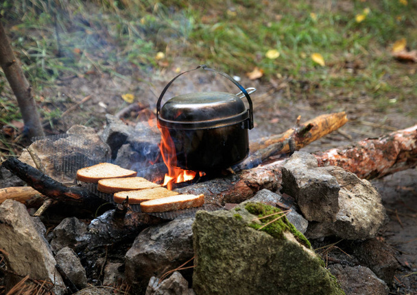 石、キャンプファイヤー、薪、やかん、グリッド上のパンから作られた暖炉 - 写真・画像