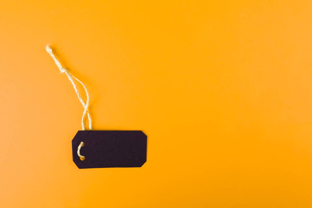 Close-up of a black tag price tag on a bright yellow background. concept of black Friday - Foto, Bild