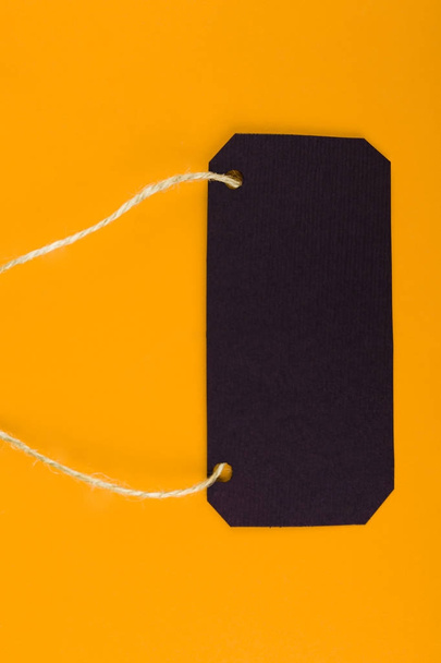 Close-up of a black tag price tag on a bright yellow background. concept of black Friday - Valokuva, kuva