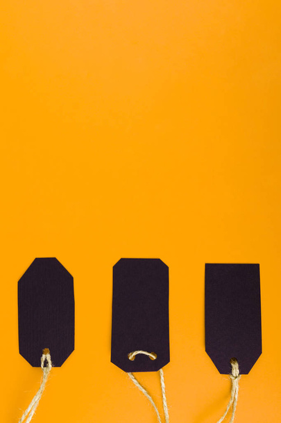 Close-up of a black tag price tag on a bright yellow background. concept of black Friday - 写真・画像