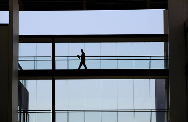 Вид силуету молодого бізнесмена в сучасному інтер'єрі офісної будівлі
 - Фото, зображення