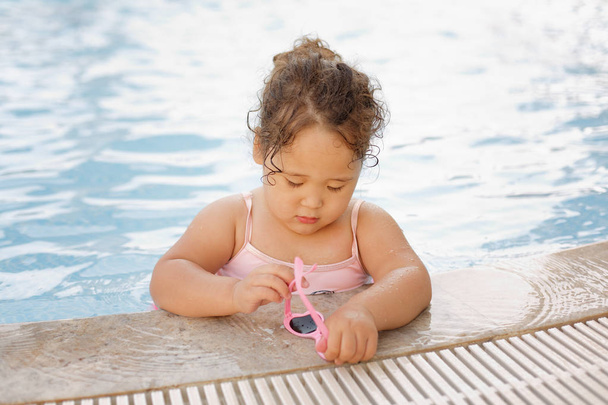 Pretty little kazakh curly girl playing by the swimming pool - Фото, изображение