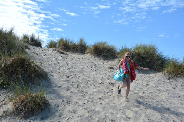 Dívka s plavání věci běží písečných dun pod ním - Fotografie, Obrázek