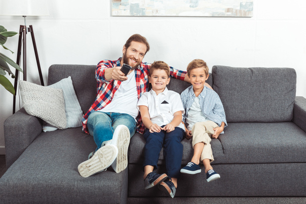 padre con hijos viendo la televisión
 - Foto, Imagen