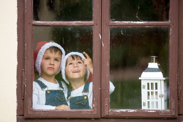 Two cute boys, brothers, looking through a window, waiting for S - Foto, immagini