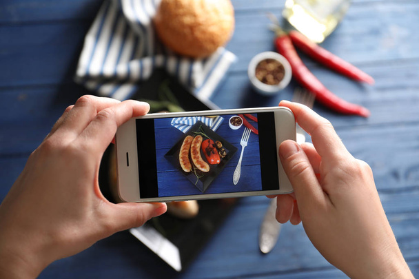 Female blogger taking photo of food with smartphone indoors - 写真・画像