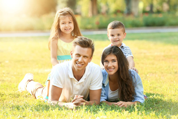 Szczęśliwa rodzina, leżąc na trawie w parku - Zdjęcie, obraz