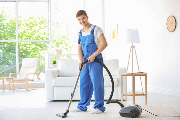 Man cleaning white carpet with vacuum in living room - Foto, immagini