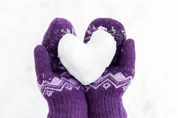 female hands in warm knitted mittens keep the heart from snow ag - Photo, Image