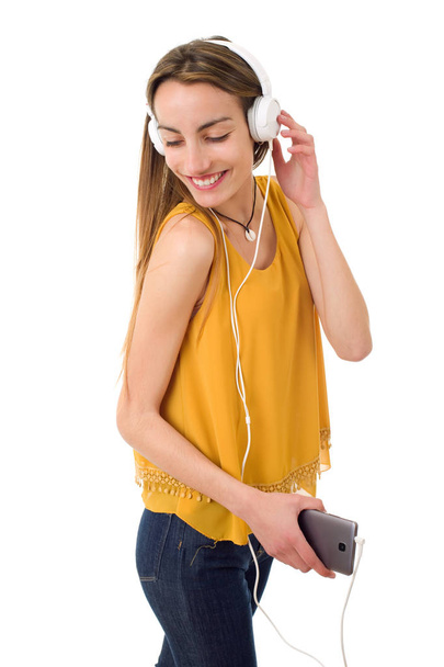 Όμορφη νεαρή γυναίκα ακούει μουσική με ακουστικά, απομονωμένο - Φωτογραφία, εικόνα