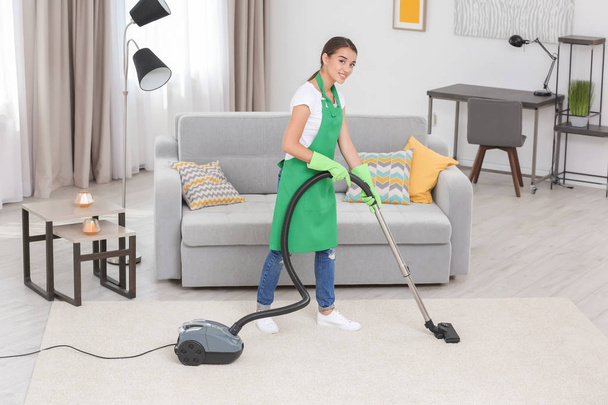 Woman cleaning carpet with vacuum  - Fotó, kép