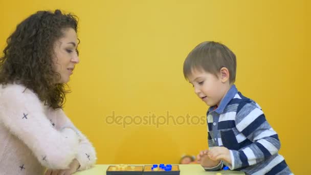 woman playing checkers with boy - Filmati, video