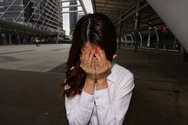 Jonge Aziatische zakenvrouw met handen op gezicht benadrukt in crisis ogenblik. Bezorgd bedrijfsconcept. - Foto, afbeelding