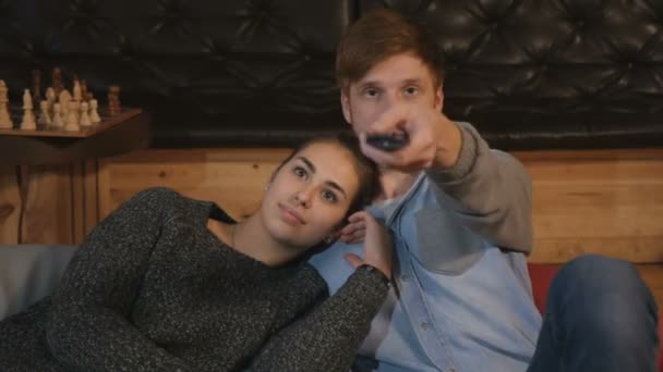 Young couple in love sitting on the floor on the pillows. People watching TV together.  - Záběry, video
